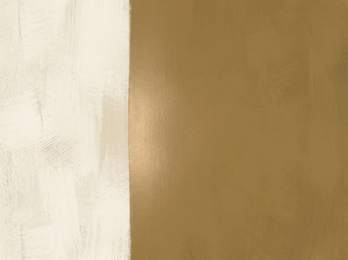 Macro close-up of a freshly cut-in paint edge where aged brass meets warm bone in a clean vertical line, with visible roller and brush-nap texture and a soft warm sheen tracing the seam
